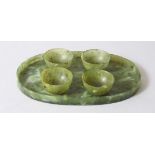 A CHINESE MOTTLED GREEN JADE OVAL TRAY AND FOUR TEA BOWLS, tray 16cm wide.