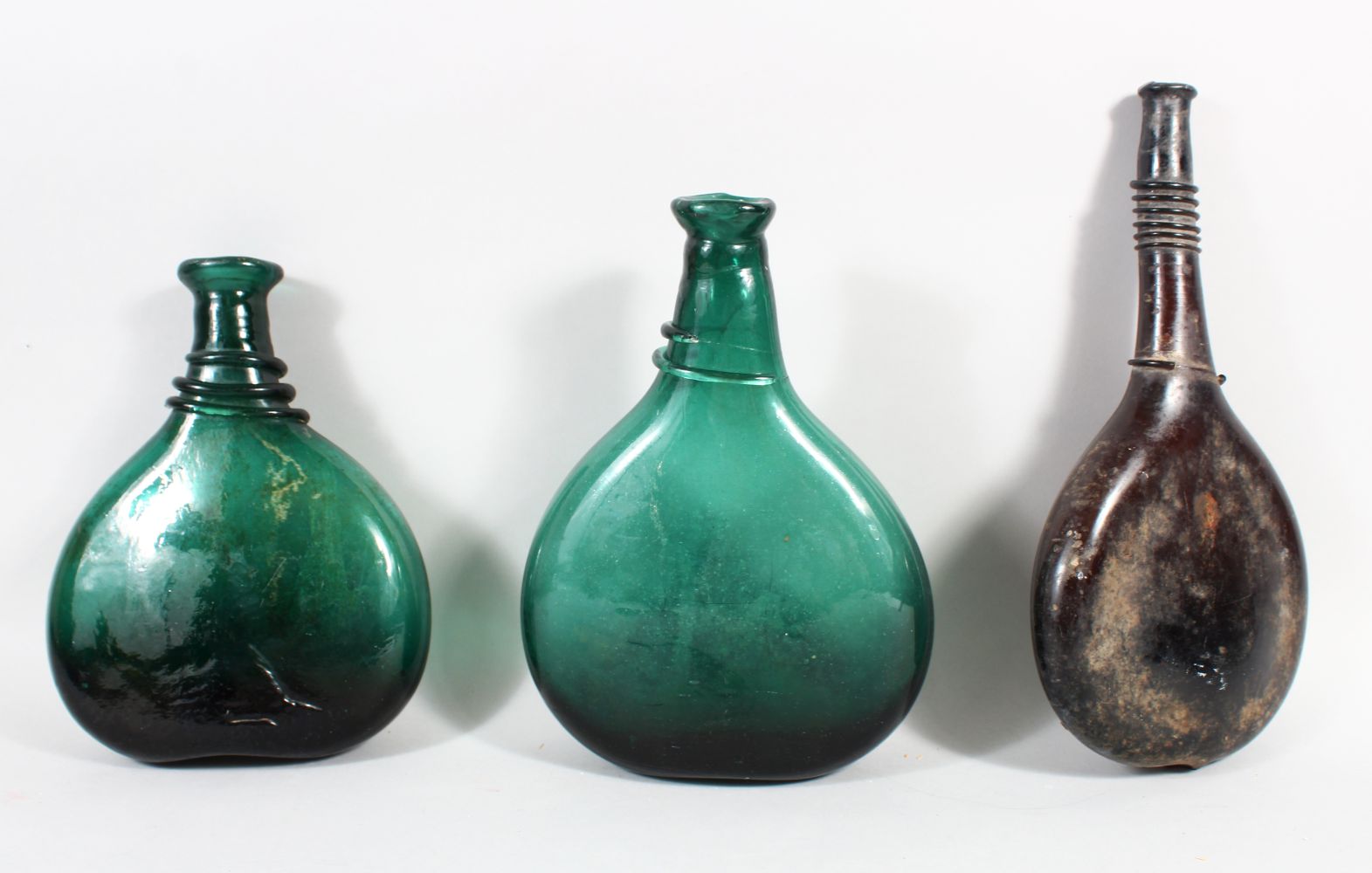 THREE EARLY QAJAR GLASS BOTTLES, 25cm high (3).