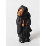 A JAPANESE MEIJI PERIOD CARVED EBONY NETSUKE OF A FIGURE, the figure stood wearing a cowl, the