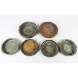 SIX VARIOUS BRONZE KHORASAN PLATES, some with engraved decoration, 15cm im diameter and larger.