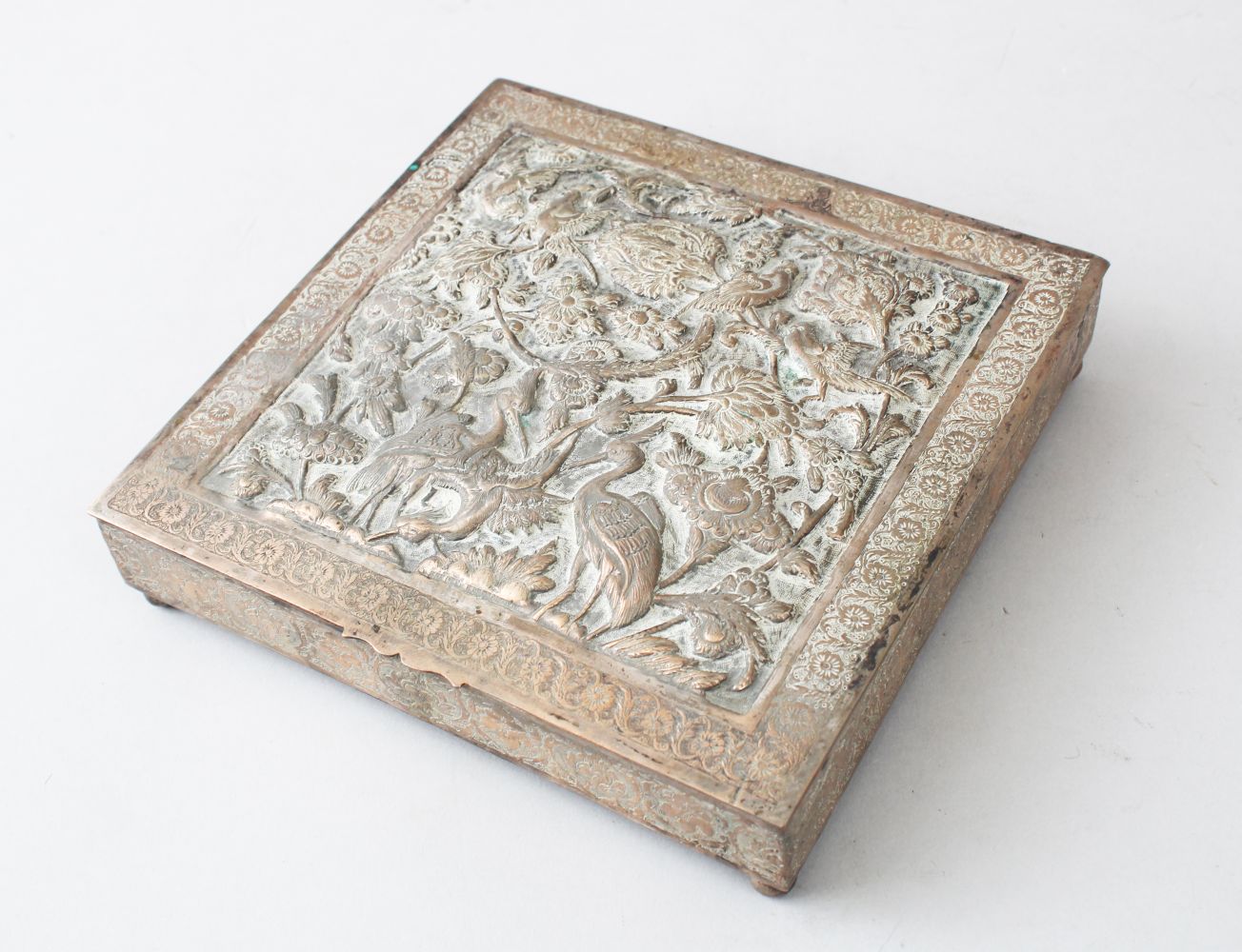 LATE 19TH CENTURY PERSIAN WHITE METAL BOX, the hinged cover embossed with birds and foliage within