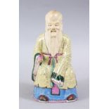 A 19TH CENTURY CHINESE FAMILLE ROSE PORCELAIN FIGURE OF SHOU LAO, in a seated pose holding a