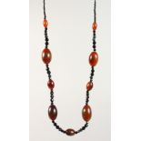 A GOOD CHINESE RHINO HORN BEAD NECKLACE, with nine oval beads of various size, interspaced with a