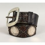 AN UNUSUAL LEATHER BELT, mounted with eight silver coins. 47.5ins long.