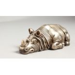 A CAST SILVER MODEL OF A RECUMBENT RHINOCEROS, marks to base. 5ins long.