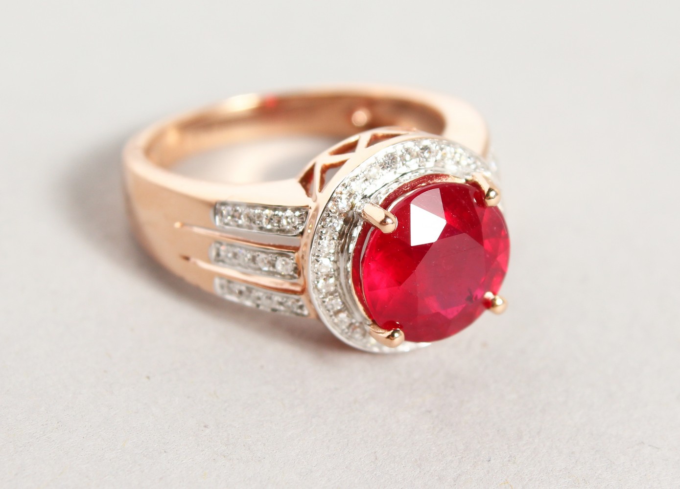 A 14K ROSE GOLD AND DIAMOND RING, set with an oval cut ruby approx. 4ct, diamonds approx. 0.48ct