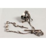 A CAST SILVER SKULL SNUFF BOX, on a chain depicting bones.