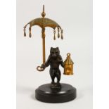 A SMALL BRONZE OF A BEAR, holding a lamp and parasol, on a circular marble base. 5.25ins high.