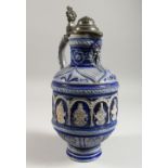 A CONTINENTAL STONEWARE JUG, with blue glazed, moulded decoration and pewter lid. 13ins high.