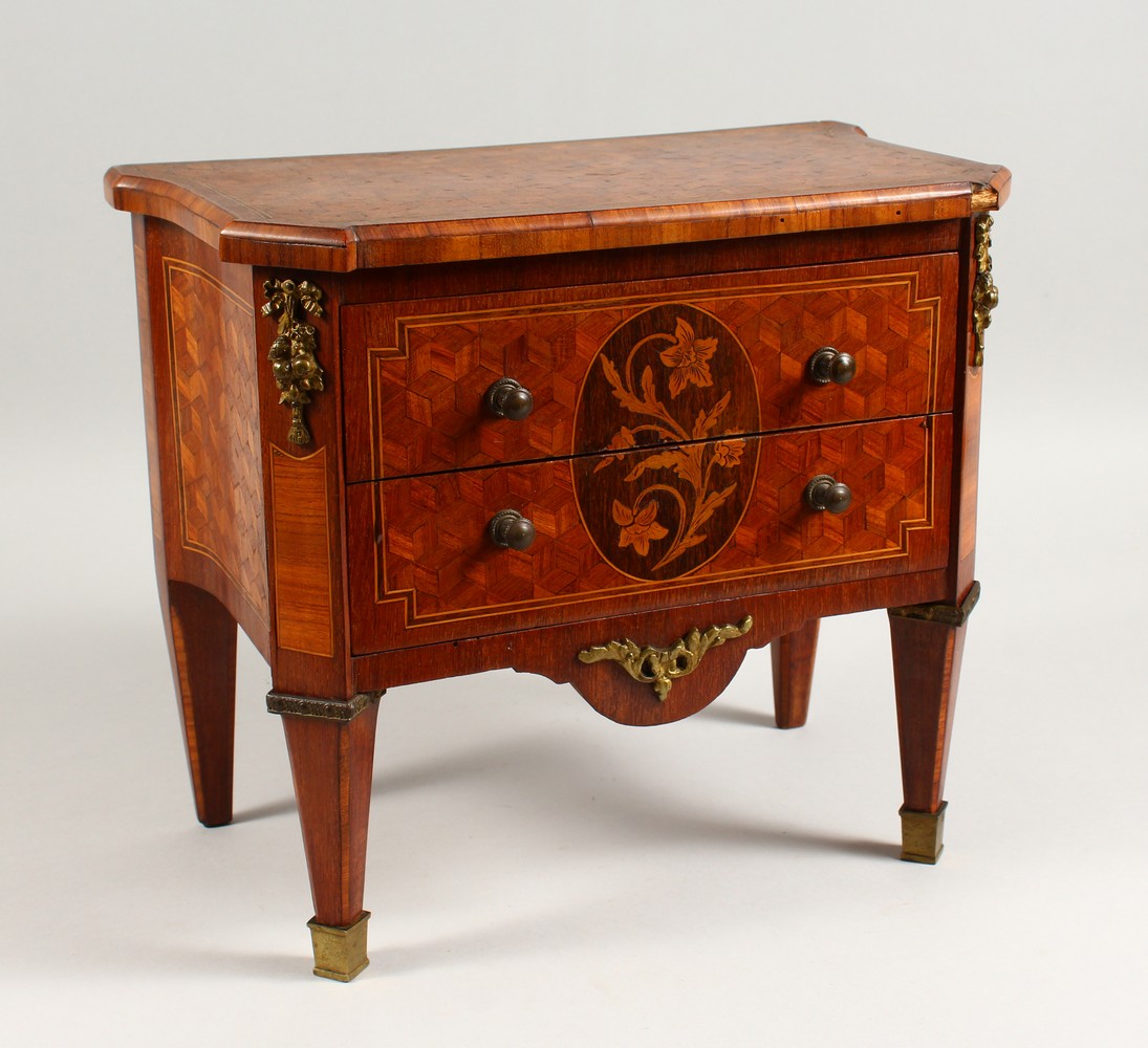 A MINIATURE FRENCH PARQUETRY AND MARQUETRY TWO DRAWER COMMODE, on tapering legs. 12ins wide.