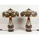 A PAIR OF TIFFANY STYLE TABLE LAMPS, with illuminated stain glass bases and shades. 24ins high.