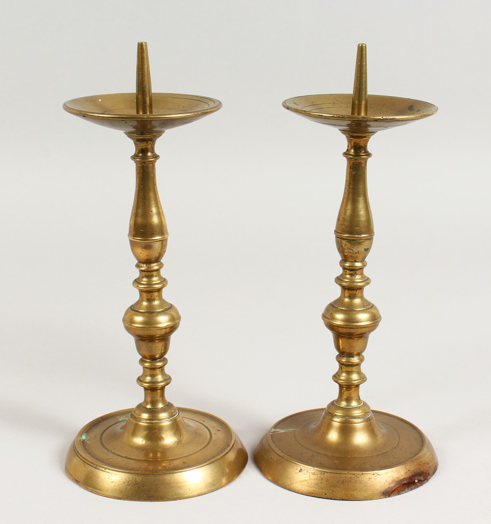 A PAIR OF EARLY BRASS CANDLESTICKS, with broad drip pans, on circular bases. 10ins high.