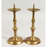 A PAIR OF EARLY BRASS CANDLESTICKS, with broad drip pans, on circular bases. 10ins high.