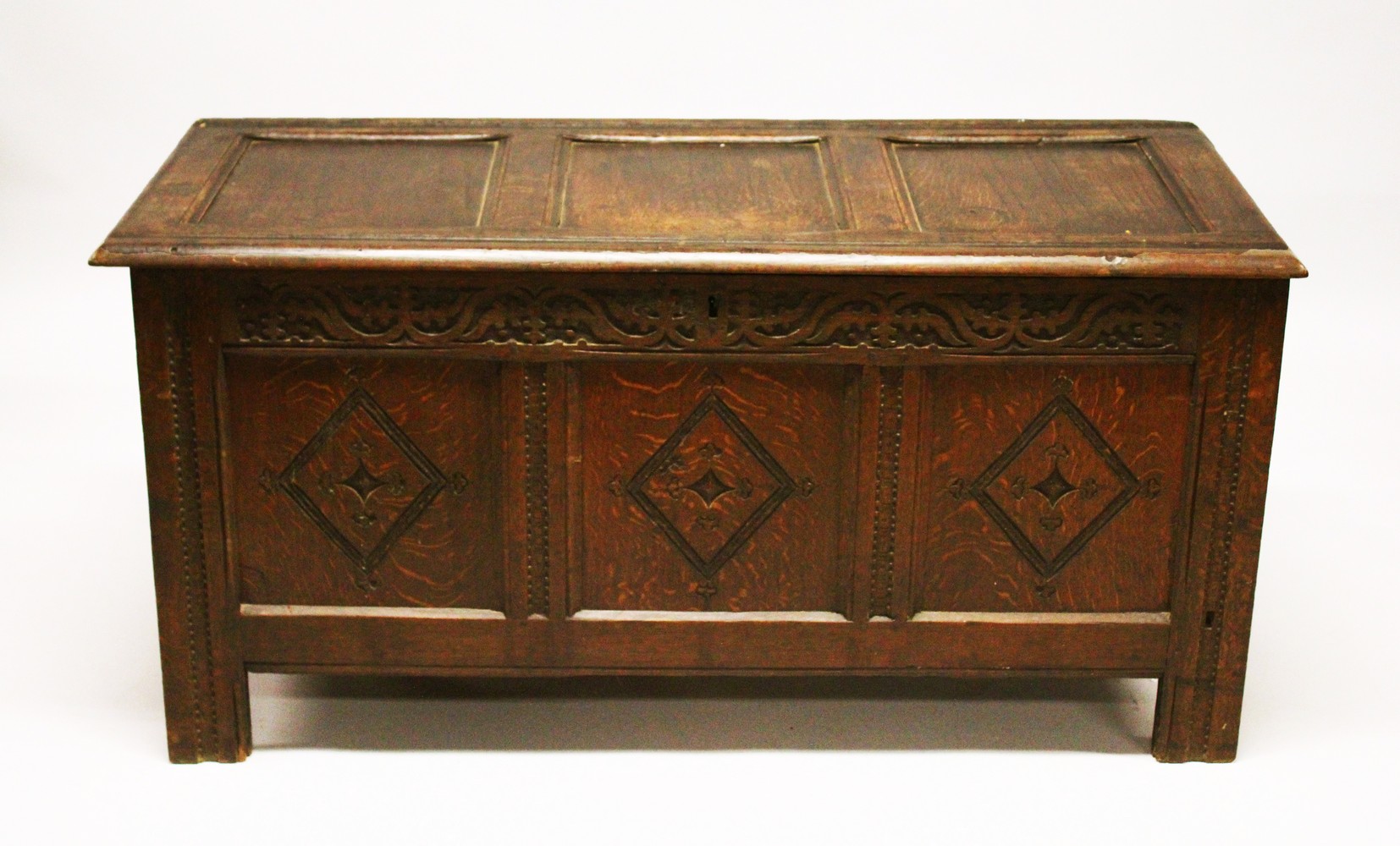 AN 18TH CENTURY OAK COFFER, with triple panelled top and front, with carved decoration. 4ft 3ins