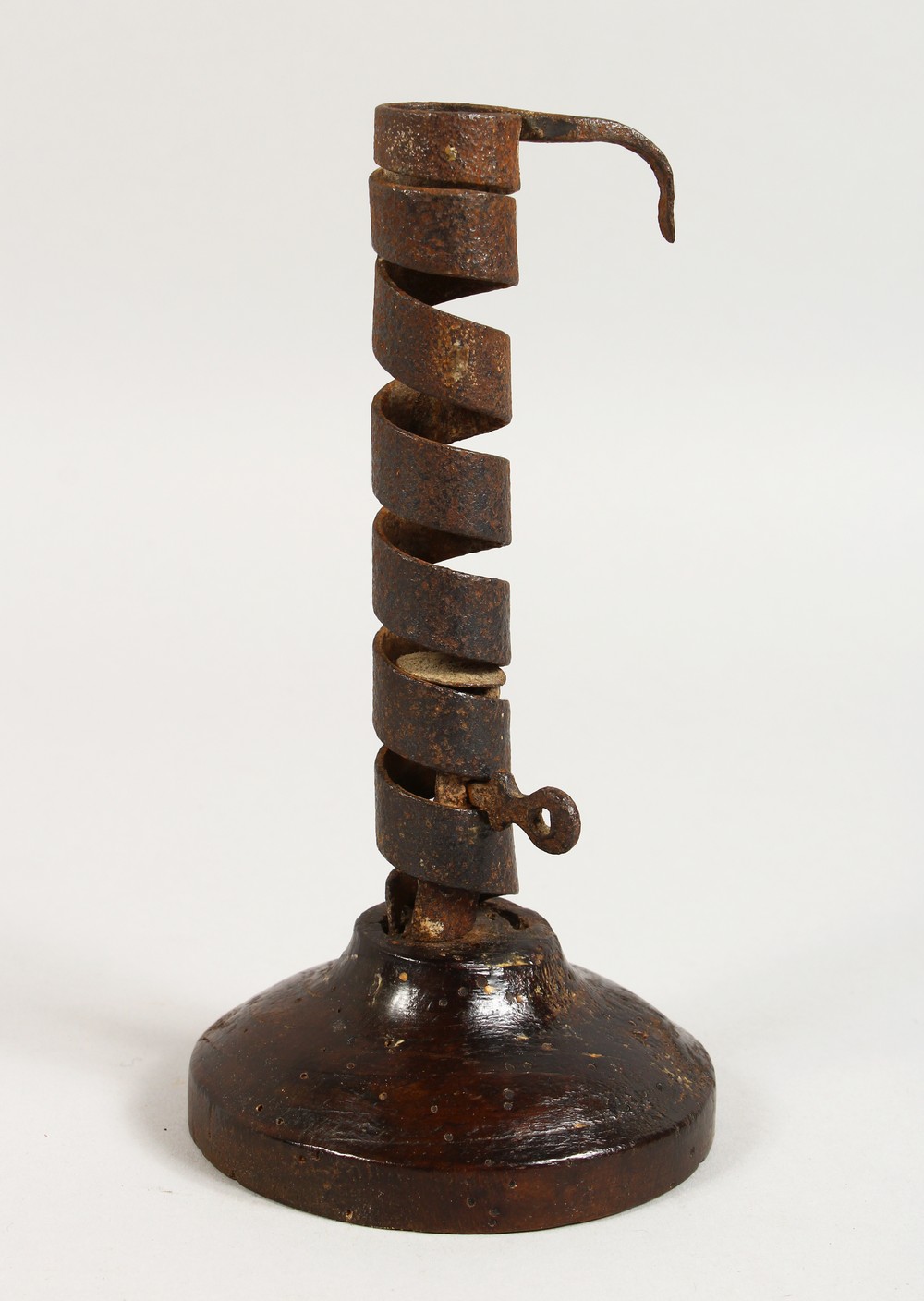 AN EARLY WROUGHT IRON CANDLESTICK, on a turned wood base. 7.5ins high.