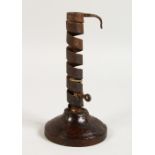 AN EARLY WROUGHT IRON CANDLESTICK, on a turned wood base. 7.5ins high.