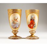 A GOOD PAIR OF 19TH CENTURY GILDED GLASS PEDESTAL GOBLETS, one painted with a three-quarter length