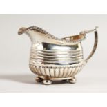 A GEORGE III CREAM JUG, with gadrooned edge and ribbed body. London 1815.