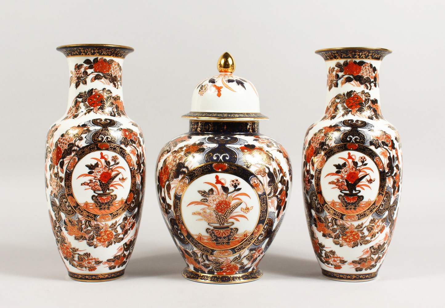 A JAPANESE IMARI GARNITURE, comprising a pair of vases and ginger jar and cover. Vases: 10.5ins