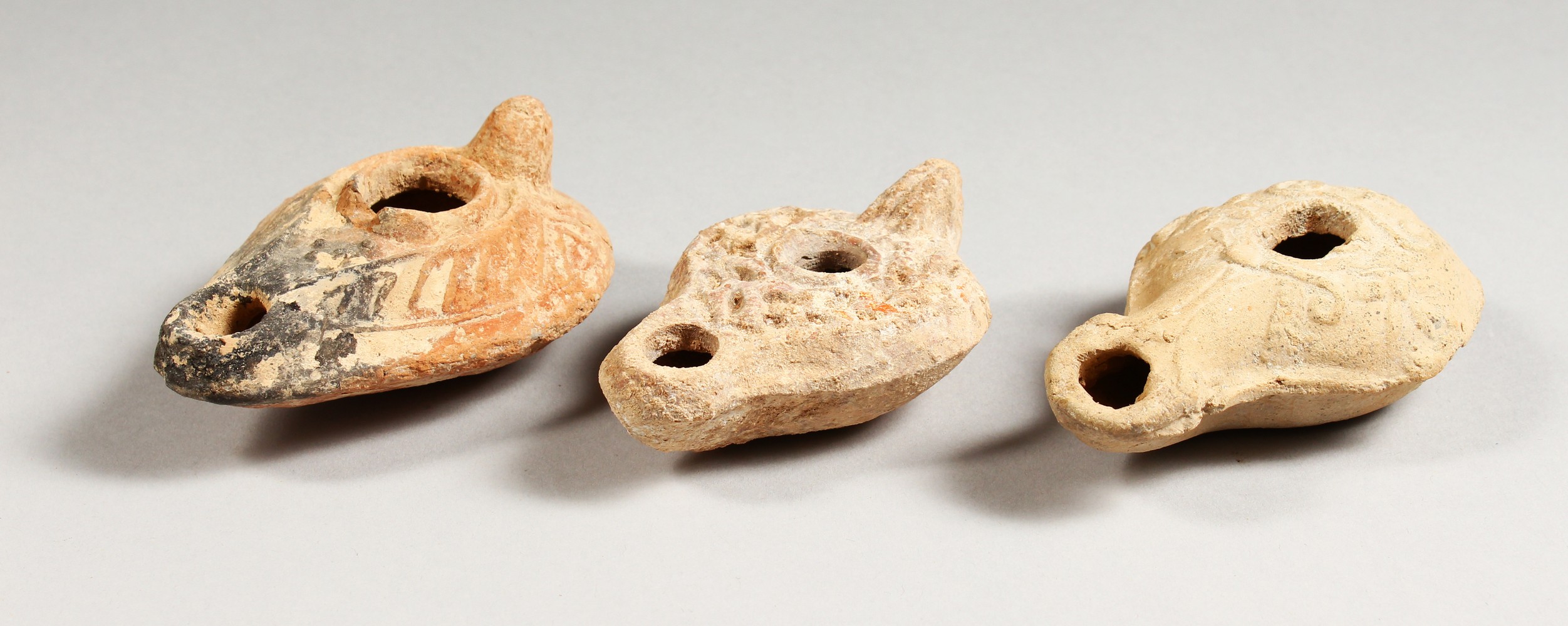 THREE ROMAN TERRACOTTA OIL LAMPS.