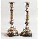 A PAIR OF RUSSIAN SILVER CANDLESTICKS, with fluted column, on a circular base with three feet. 12ins