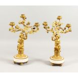 A GOOD PAIR OF LOUIS XVI DESIGN ORMOLU AND WHITE MARBLE CANDLESTICKS, with cupids holding three