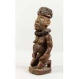 A CARVED WOOD AFRICAN FIGURE, a kneeling female nude wearing a large collar. 20ins high.