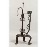 AN ORNATE WROUGHT IRON CANDLE HOLDER, on three feet. 18ins high.
