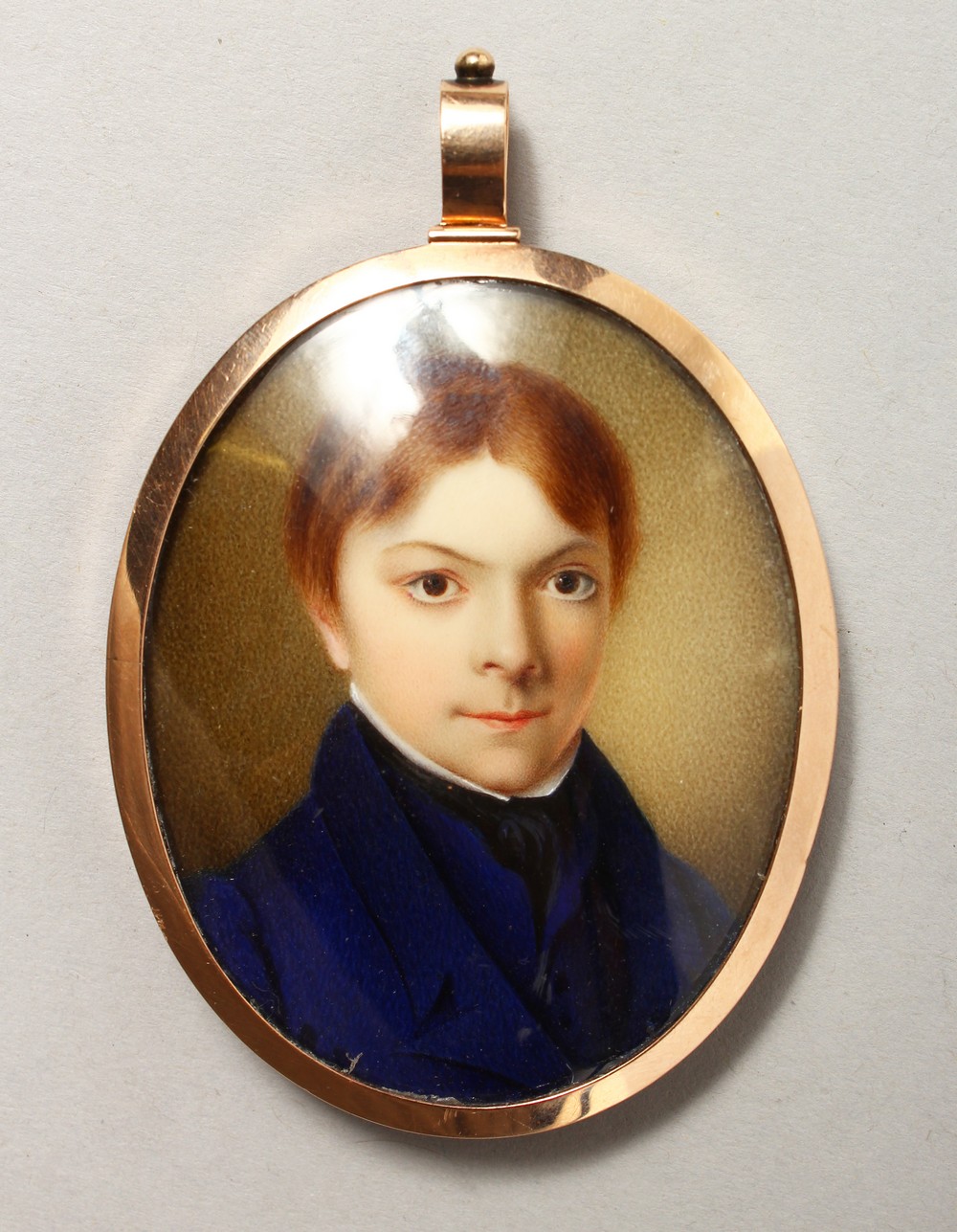 AN EARLY 19TH CENTURY PORTRAIT MINIATURE of a young boy in a blue coat, plaited hair to reverse. 2.