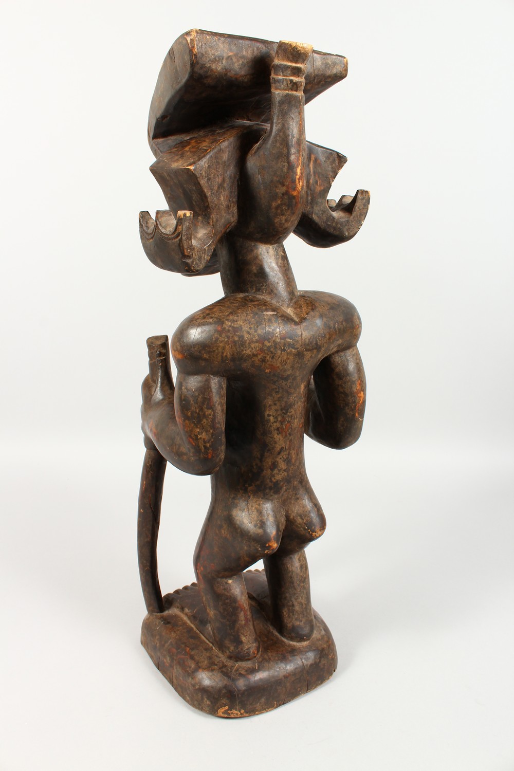 A CARVED WOOD TRIBAL STANDING FIGURE, of a man with headdress, holding a staff. 23ins high. - Image 4 of 6