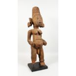 A LARGE CARVED WOOD AND PAINTED TRIBAL FIGURE, of a standing female, on a later base. 31ins high.