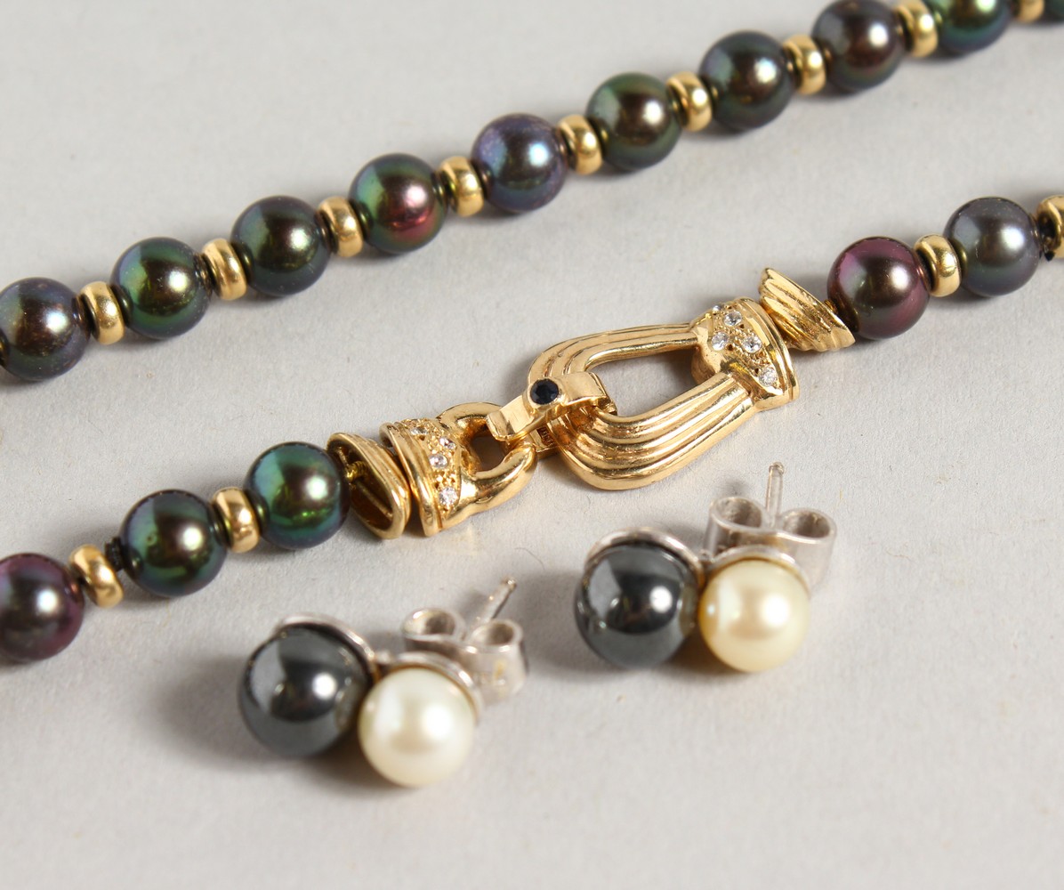 A GOOD BLACK PEARL NECKLACE, with ornate gold and diamond clasp, with a pair of similar earrings.