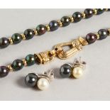 A GOOD BLACK PEARL NECKLACE, with ornate gold and diamond clasp, with a pair of similar earrings.