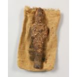 A TERRACOTTA USHABTI, in a hessian bag. 8ins long.