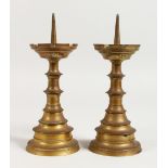 A PAIR OF TURNED BRASS CANDLESTICK, with castellated drip pans. 8ins high.