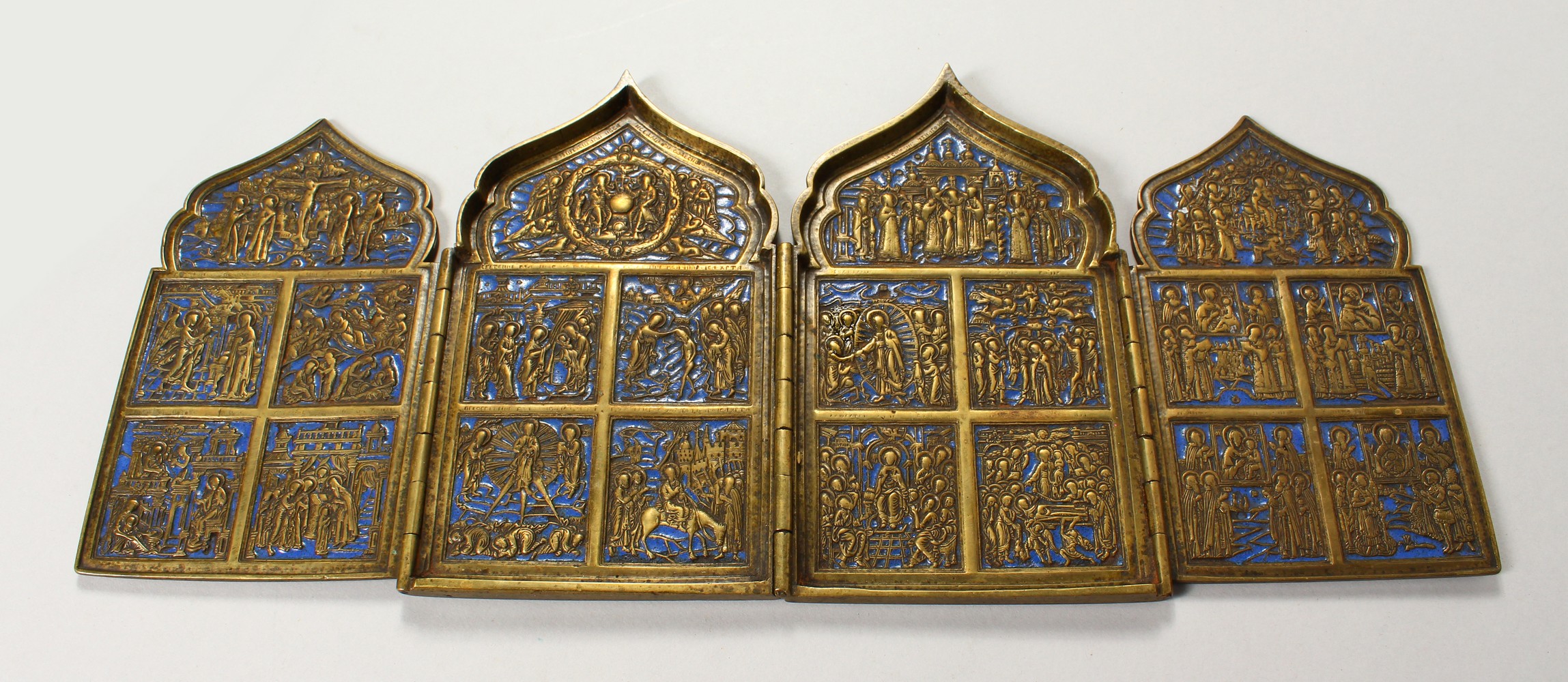 A FOUR PIECE RUSSIAN BRASS AND BLUE ENAMEL FOLDING ICON, with sixteen small panels, 1.75ins square