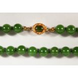 A JADE BEAD NECKLACE, with gold coloured clasp. 23ins long.