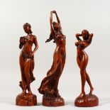A SET OF THREE SMALL CARVED WOOD SCULPTURES OF STANDING FEMALE FIGURES. 7ins, 8ins and 9ins high.