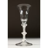 A GEORGIAN WINE GLASS with inverted bell shaped bowl and three knops to the stem and white air