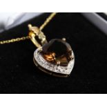 A 9CT GOLD HEART SHAPED TOPAZ PENDANT AND CHAIN.