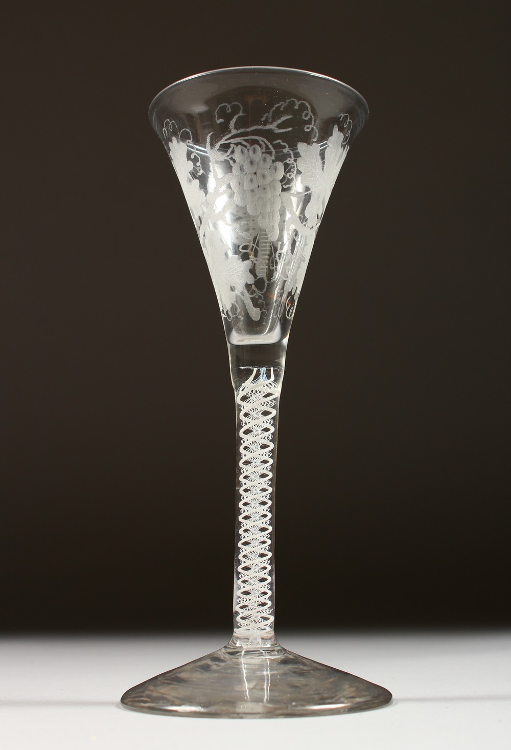 A GEORGIAN WINE GLASS with tapering bowl engraved with fruiting vines, with air twist stem. 6.5ins