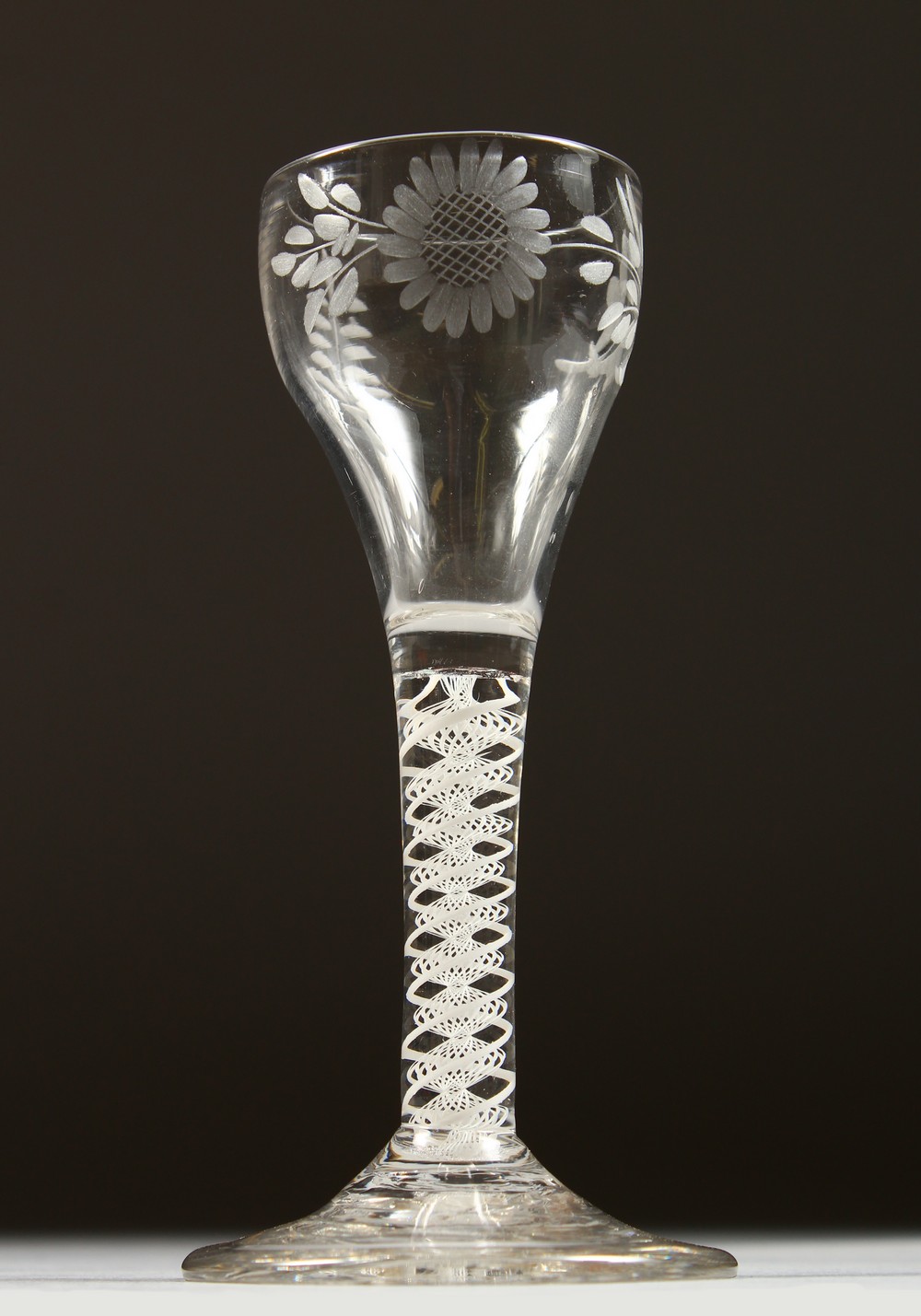 A GEORGIAN WINE GLASS, the bowl engraved with sunflowers, with white air twist stem. 5.5ins high.