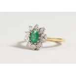 A 9CT GOLD OVAL, EMERALD AND DIAMOND CLUSTER RING.