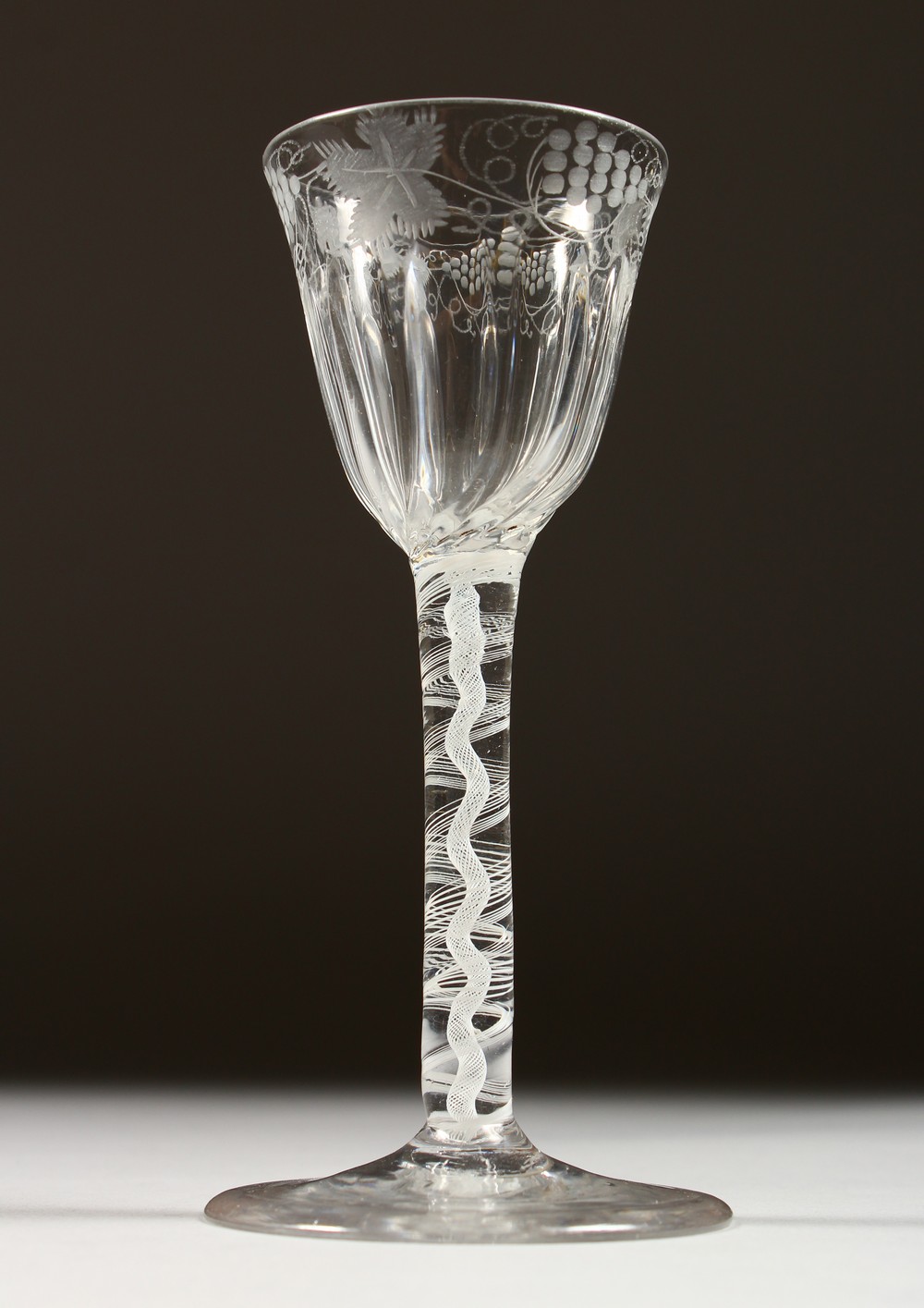 A GEORGIAN WINE GLASS, the fluted bowl engraved with flowers and butterflies, with white air twist