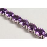 A SILVER BRACELET set with sixteen oval cut amethysts.