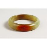 A MOTTLED JADE BANGLE. 3ins diameter.