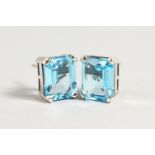 A PAIR OF SILVER SET EMERALD CUT BLUE TOPAZ EARRINGS.