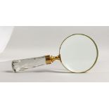A BRASS MAGNIFYING GLASS with cut glass handle.