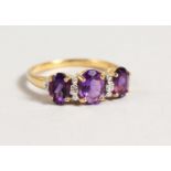 A 9CT GOLD THREE STONE AMETHYST AND DIAMOND RING.