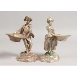 A GOOD PAIR OF CAST PLATED SALTS of a young boy and girl carrying baskets. 5.5ins high.